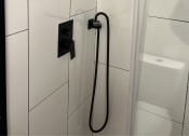 Thumbnail 21 of 49 - The Retreat at Indian Lake - Renovated Studio Shower with White Tile and Black Hardware