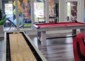 Thumbnail 58 of 60 - Fusion Orlando apartments clubhouse recreation amenities like tabletop shuffle board, pool table with red felt, and gym.