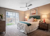 Thumbnail 8 of 36 - Large bedroom in the Stadium 700 luxury apartments in Arlington, TX with queen bed, ceiling fan, and large sliding glass door