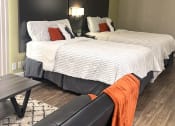 Thumbnail 18 of 60 - Fusion Orlando furnished studio apartment Orlando bedroom with two full beds. Beds have modern grey headboards, striped duvets, and orange and white pillows.