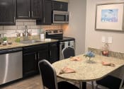 Thumbnail 20 of 60 - Fusion Orlando studio apartment kitchen with stainless steel appliances, espresso cabinets, and breakfast nook with three chairs.