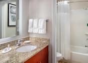 Thumbnail 6 of 18 - A bathroom with a white tub, sink, and towel at Fusion Buckhead Apartments.