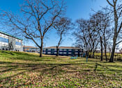 Thumbnail 23 of 27 - Exterior of The Canvas Apartments in Nashville with a blue facade is surrounded by bare trees.