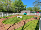Thumbnail 30 of 49 - Pet park at the Retreat at Indian Lake apartments in hendersonville with dog agility course on brown mulch track surrounded by green grass.