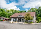 Thumbnail 13 of 36 - The Retreat at Indian Lake leasing office with a brown roof and a parking lot in front.