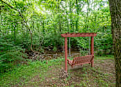 Thumbnail 35 of 36 - A wooden swing set is situated in a green forest at The Retreat at Indian Lake Apartments in Hendersonville TN.
