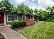 Thumbnail 26 of 36 - A red door is on the left side of a grey building at The Retreat at Indian Lake Apartments in Hendersonville TN.