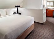 Thumbnail 7 of 18 - A bed with white pillows and a white bedspread in a room with a carpeted floor in a two bedroom apartment at Fusion Buckhead.
