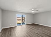 Thumbnail 8 of 38 - A living room with a ceiling fan and sliding glass doors leading to a deck at Mandarin Bay Apartments.