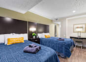 Thumbnail 8 of 41 - Two beds with blue bedspreads and yellow pillows in a bedroom at Fusion Orlando.