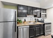 Thumbnail 5 of 41 - A kitchen with black cabinets and a stainless steel refrigerator.