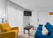 Thumbnail 11 of 41 - A living room with a yellow chair, a blue couch, and a flat screen TV mounted on the wall.