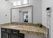 Thumbnail 17 of 41 - A bathroom with a granite countertop and a large mirror.