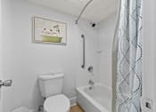 Thumbnail 18 of 41 - A white toilet sits next to a white bathtub in a bathroom.