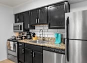 Thumbnail 15 of 41 - A kitchen with black cabinets and a stainless steel refrigerator.