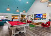 Thumbnail 27 of 41 - A pool table is in the middle of a room with a TV and a bar at the Fusion Orlando clubhouse