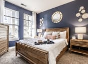 Thumbnail 9 of 28 - A furnished bedroom with blue walls, carpeted flooring, and a window.