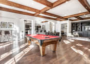 Thumbnail 21 of 28 - A pool table in a gathering space with seating areas and hardwood-style flooring.