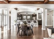 Thumbnail 22 of 28 - A dining room table surrounded by eight chairs, next to a kitchen, on hardwood-style flooring.