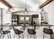 Thumbnail 23 of 28 - Four bar stools facing a kitchen with stainless steel appliances and light fixtures at The Fort.