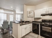 Thumbnail 6 of 29 - Clermont Apartments - Kitchen With Hardwood Floors, Black Appliances, And White Cabinets.