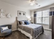 Thumbnail 2 of 29 - Eagle Creek, IN Apartments Near Downtown Indianapolis - Riverchase - Spacious Bedroom With Carpet Flooring, A Ceiling Fan, And A Window With Blinds
