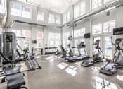 Thumbnail 3 of 28 - A fitness center with with a selection of cardio machines, weights, and TV's, surrounded by large windows.