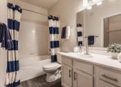 Thumbnail 14 of 29 - a bathroom with a white sink and toilet next to a white bathtub with a shower curtain