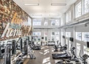 Thumbnail 13 of 28 - Fitness center with a selection of workout machines and weights, surrounded by large windows.