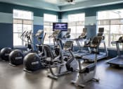 Thumbnail 15 of 25 - The fitness center at Austin Park Apartments provides both cardio equipment and free weights for residents' exercise needs.