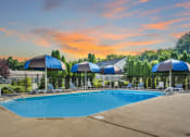 Thumbnail 4 of 16 - a swimming pool with blue umbrellas and white lounge chairs