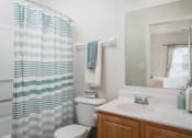 Thumbnail 8 of 21 - Bright bathroom at Catalina Club with a white sink and toilet next to a decorative blue-and-white shower curtain.