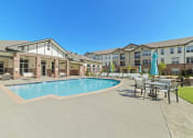 Thumbnail 19 of 25 - The resort-style swimming pool and sundeck at Austin Park Apartments feature shaded tables and comfortable lounge chairs.