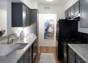 Thumbnail 1 of 19 - Modern kitchen with black appliances, granite countertops, sleek cabinetry, and wood-style flooring in a two-bedroom apartment at The Boulevard in Florence, KY