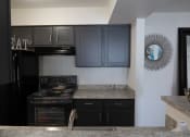 Thumbnail 8 of 19 - Kitchen with granite countertops and black appliances in a modern apartment setting