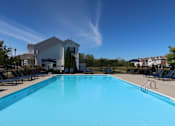 Thumbnail 35 of 55 - a swimming pool with chairs and a building in the background