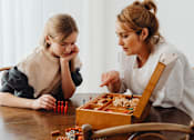 Thumbnail 41 of 55 - A woman and a girl are playing a board game at a table.
