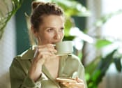Thumbnail 38 of 55 - A woman is drinking from a green mug.