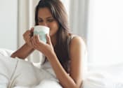 Thumbnail 43 of 55 - A woman is drinking from a blue and white mug.