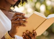 Thumbnail 40 of 55 - A woman is reading a book outdoors.