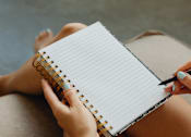 Thumbnail 45 of 55 - A person is writing in a notebook with a pen.