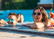 Thumbnail 50 of 55 - Three people sunbathing by a pool.