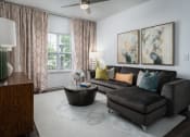 Thumbnail 1 of 25 - Spacious living room with brown leather couch, round coffee table, ceiling fan, and natural light at The Coleman in Canal Winchester, OH
