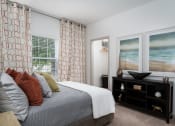 Thumbnail 9 of 25 - Furnished bedroom with plush carpeting, large bed, dresser, window, and modern decor at The Coleman in Canal Winchester, OH