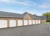 Thumbnail 24 of 25 - Brick building exterior featuring three garage doors and driveway access at The Coleman
