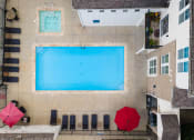 Thumbnail 17 of 28 - Birds eye view of a swimming pool with lounge chairs and two red umbrellas.