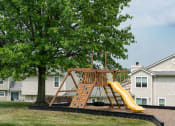 Thumbnail 19 of 23 - Apartments for Rent in Florence KY - Windridge Townhomes - Playground with Rock Wall, Slide, and Climbing Equipment Surrounded By Lush Grass and Large Tree