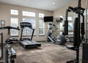 Thumbnail 16 of 23 - A spacious home gym with a variety of equipment including a treadmill, stationary bike, and weight machines.