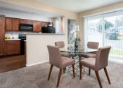 Thumbnail 7 of 23 - a dining area with a glass table and four chairs