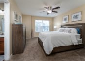 Thumbnail 2 of 23 - 1 BR Apartments in Florence KY - Windridge Townhomes - Bedroom with Bed, Dresser, Nightstand, Lamp, Ceiling Fan, and Large Window